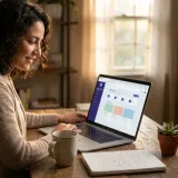 A smiling teacher at her desk at home, planning a lesson on her laptop.